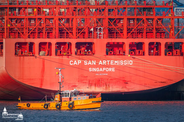 Gelbes Wasserboot fährt vor dem knallroten Riesen-Containerschiff CAP SAN ARTEMISSIO im Hamburger Hafen vorbei.