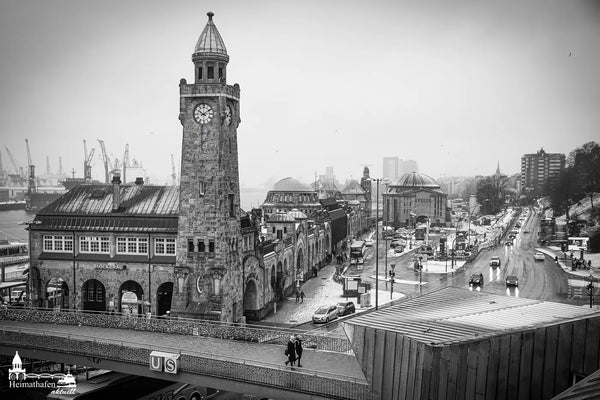 Landungsbrücken mit Pegelturm im Winter, Schneefall und nebligem Hafenhintergrund.