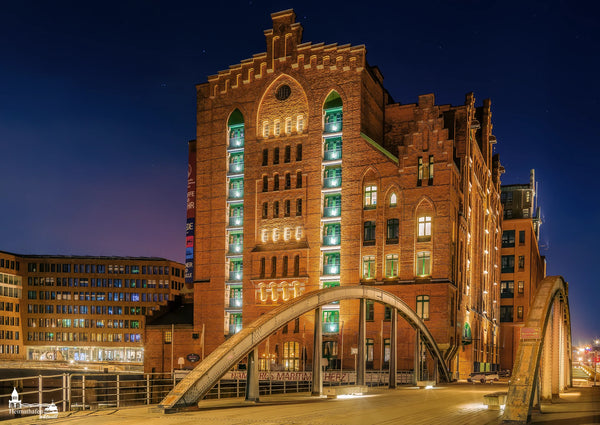 Internationales Maritimes Museum Hamburg bei Nacht mit beleuchtetem Backsteingebäude und Brücke in der HafenCity