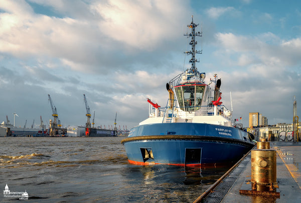 Schlepper FAIRPLAY 91 im Hamburger Hafen vor Docklandschaft und Kränen bei Sonne und Wolken