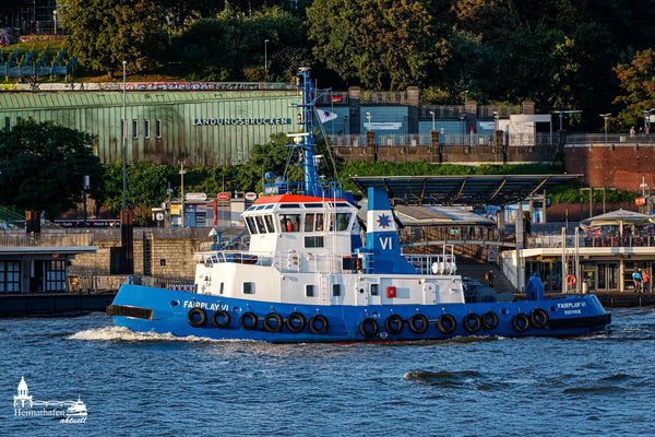 Der Schlepper FAIRPLAY VI aus Rostock fährt vor den Landungsbrücken in Hamburg entlang. Im Hintergrund sind die bekannten grünen Kupferdächer der Station zu sehen.