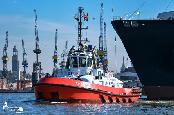 Der Hafenschlepper ZP BISON der Reederei KOTUG im Einsatz vor der Hamburger Skyline mit dem Michel und Hafenkränen im Hintergrund.